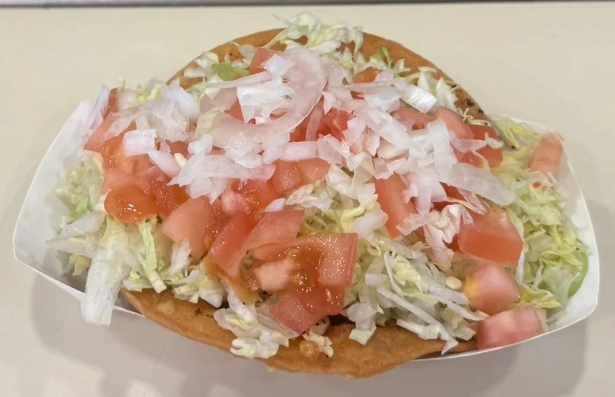 Taco with cheddar cheese, lettuce and tomatoes